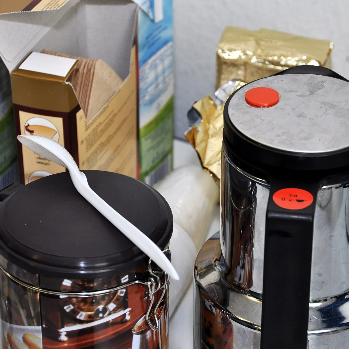 Rvs koffiethermoskan naast een blikje koffie met lepel