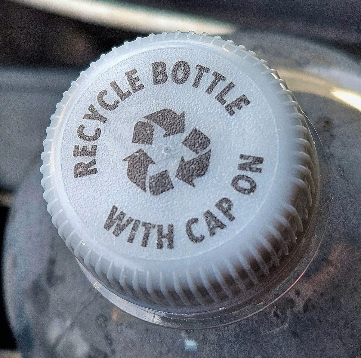 Witte plastic dop van een fles met opdruk 'recycle bottle with cap on'